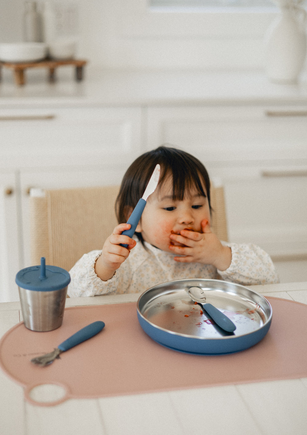 Enfant mange seul avec des ustensiles adaptés dans une cuisine familiale